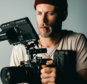 man in black knit cap holding black video camera